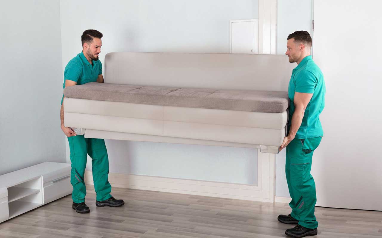 Two junk removal employees removing a sofa